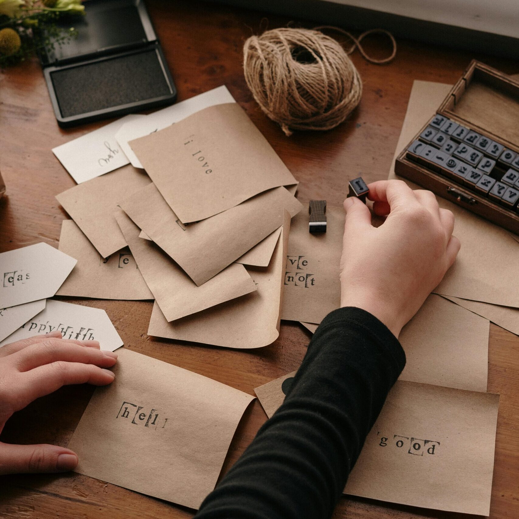 A person stamping envelopes with letters for handmade cards, showcasing creativity and craftsmanship.